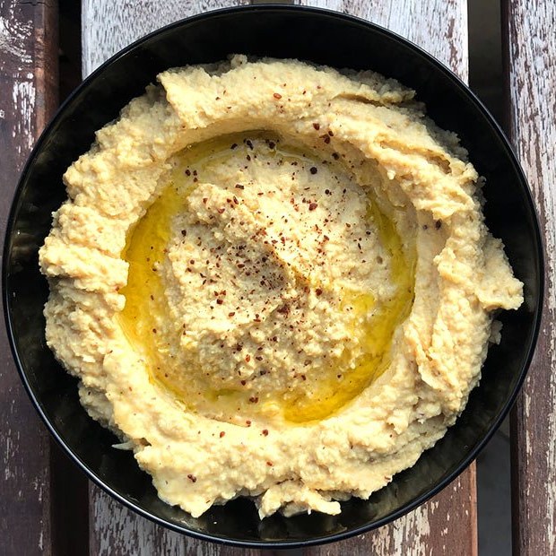 Hummus with olive oil and chilli flakes in a black bowl