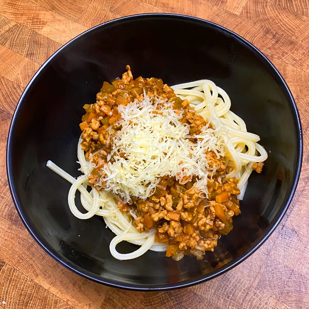 Pasta ragu with grated parmesan in a black bowl
